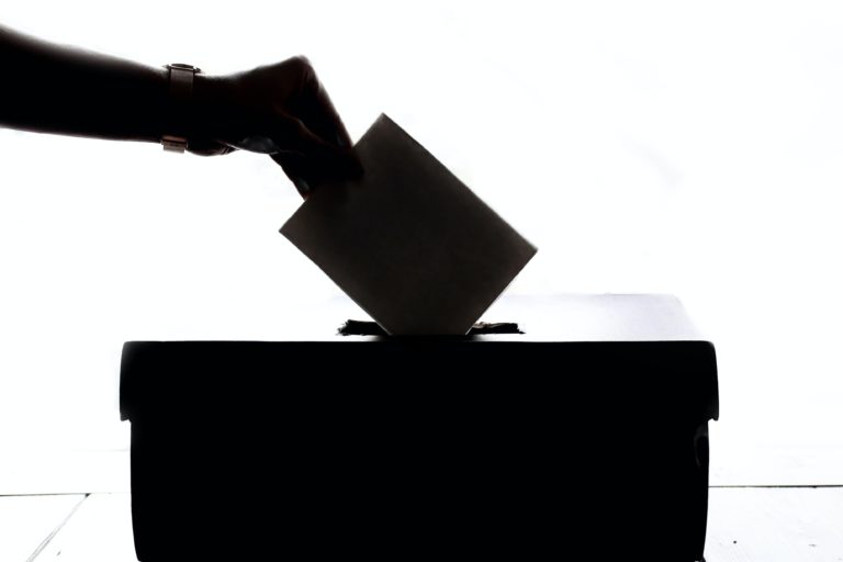 silhouette of person dropping ballot in box
