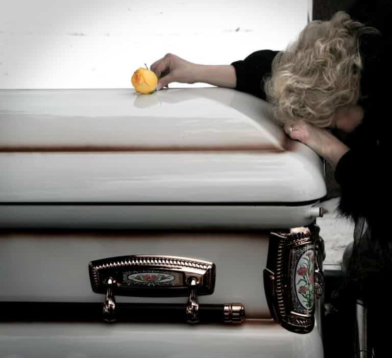 Woman laying over casket with a rose