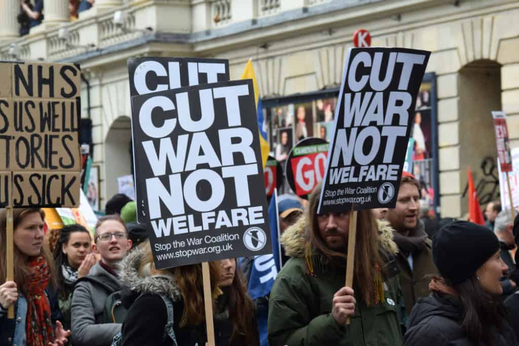 People carrying signs saying "Cut War Not Welfare" at a protest
