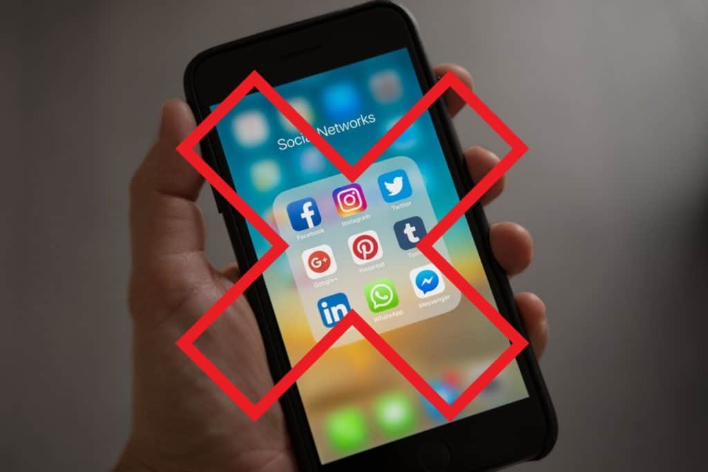 A big red X over a picture of social media displayed on a smartphone