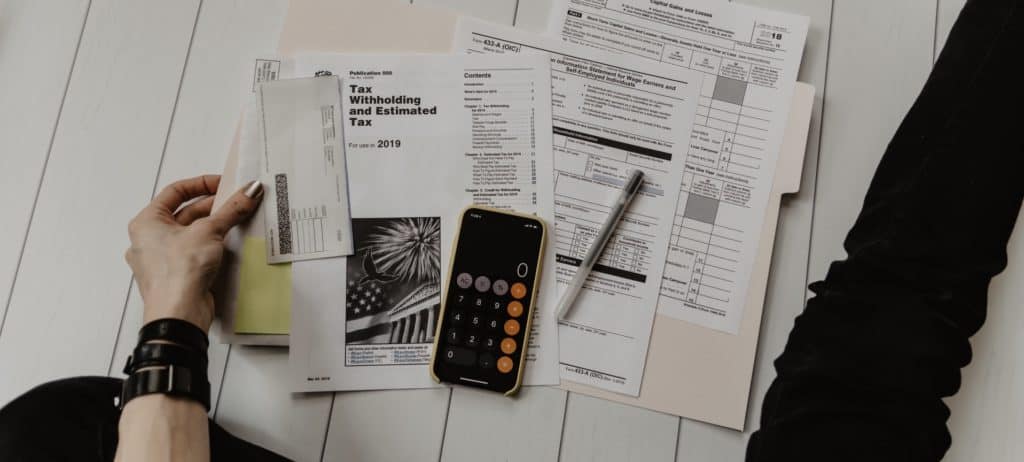 Tax forms on a desk with a calculator and pen
