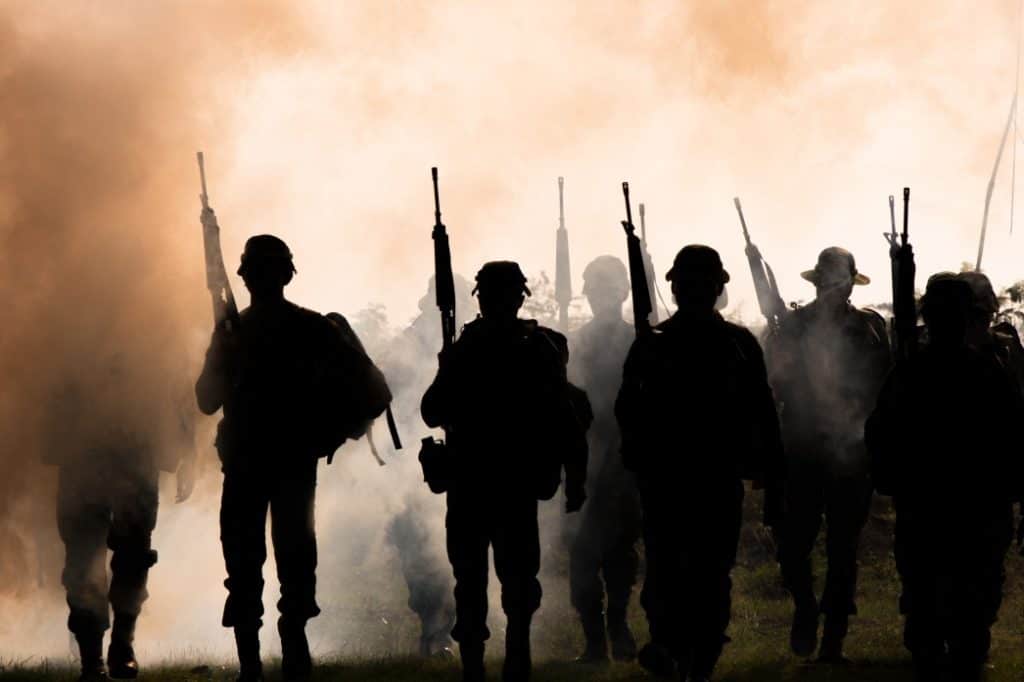 silhouette of soldiers walking through smoke