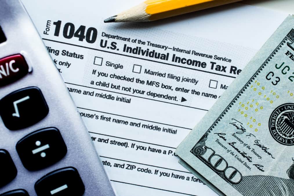 Filing federal income taxes, calculator, and $100 bill
