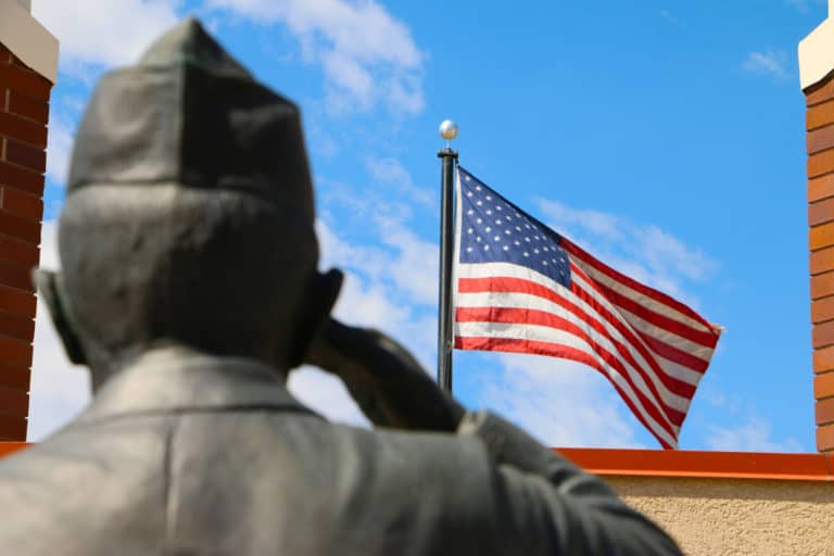 Salute to Veterans: Statue of soldier saluting with American flag flying in the background.